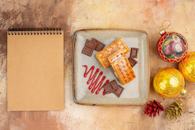 Vista dall'alto gustose torte waffle con cioccolato e giocattoli dell'albero di capodanno su sfondo chiaro