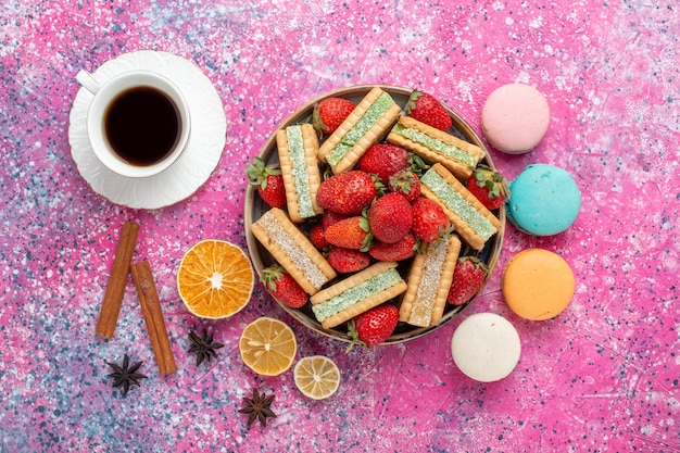 Foto gratuita vista dall'alto di deliziosi biscotti waffle con fragole rosse fresche e macarons su superficie rosa chiaro