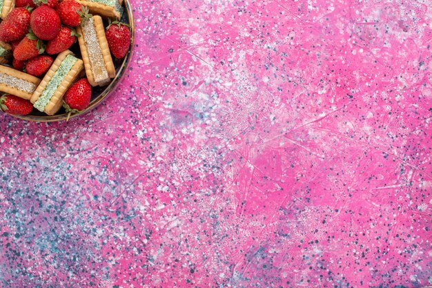 Foto gratuita vista dall'alto di gustosi biscotti waffle con fragole rosse fresche sulla superficie rosa