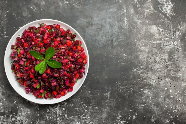 Foto gratuita vista dall'alto l'insalata di lato sinistro con verdura rossa in un piatto bianco su superficie grigia