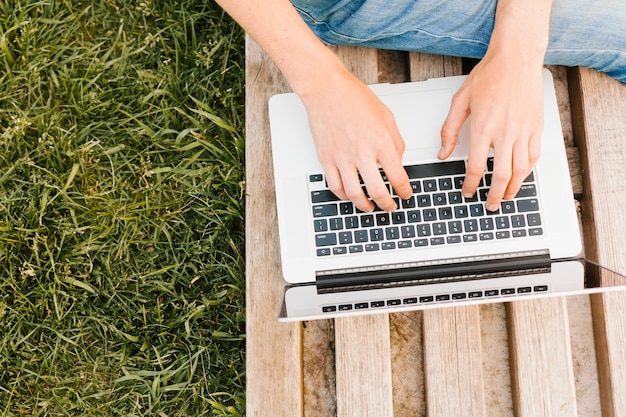 Scrittura dell'uomo di topview sul computer portatile nel parco