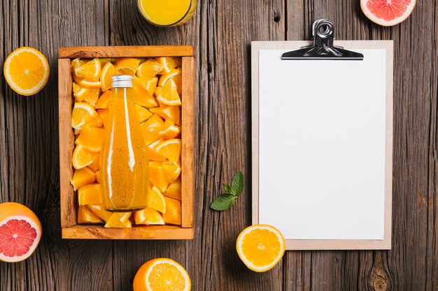 Topview orange juice and clipboard on wooden background