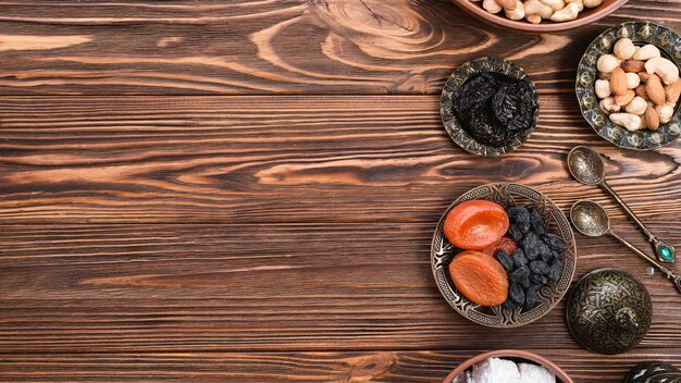 Toreutic engraved artistic metallic bowls with dried fruits and nuts on wooden surface