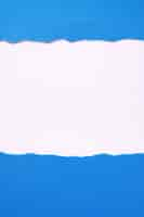 Free photo torn blue paper white background border frame vertical