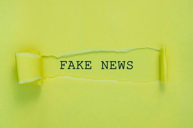 torn fake news paper on green wall