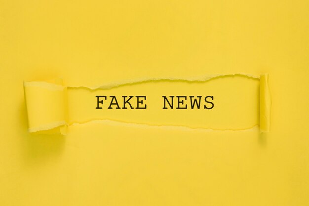 torn fake news paper on yellow wall