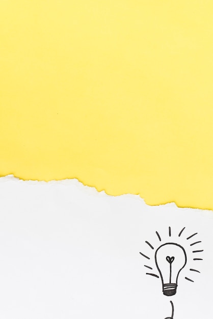 Free photo torn yellow paper with hand drawn light bulb on white background