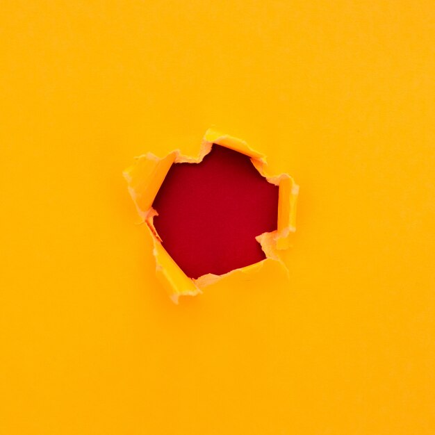 赤い段ボールの背景にテキスト用のスペースと引き裂かれた黄色い紙