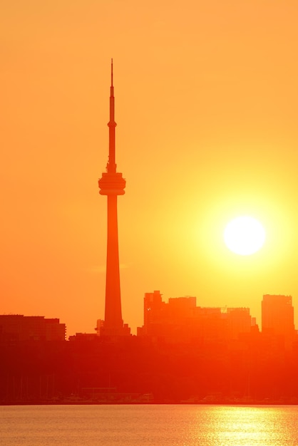 Toronto sunrise silhouette over lake with red tone.