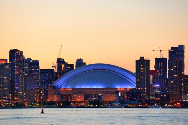 都市建築と湖の上の夕暮れ時のトロントの夕日のシルエット。