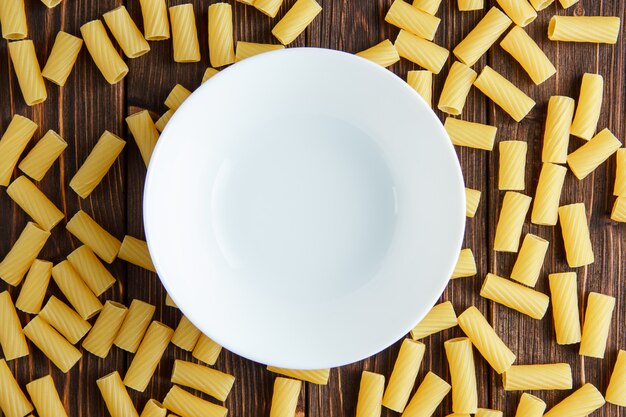 Tortiglioni pasta with empty plate flat lay on a wooden table