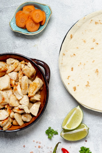 Tortilla and chicken dish near sliced carrots and lime
