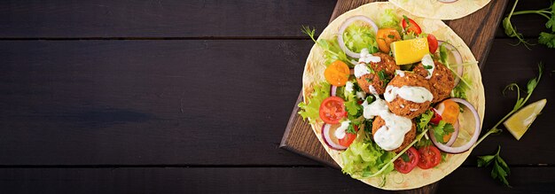 ファラフェルと新鮮なサラダのトルティーヤラップ。ビーガンタコスベジタリアンの健康食品。バナー。上面図