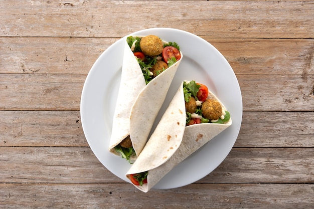 Tortilla wrap with falafel and vegetables on wooden table