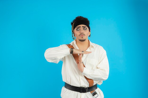 Total young pirate stand on blue background and gesture time out. High quality photo