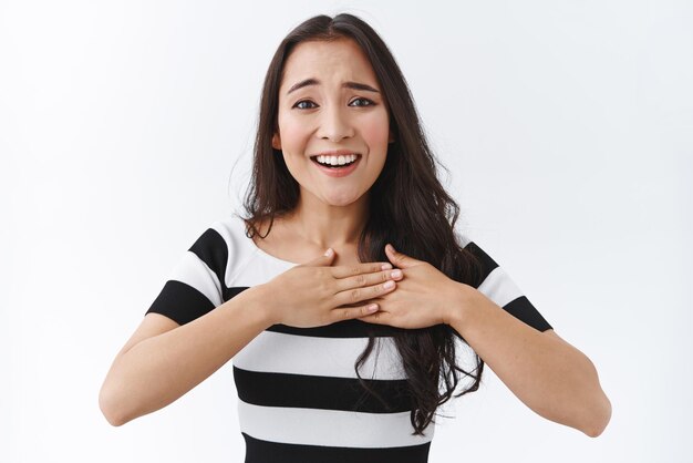 Touched and flattered silly cute asian girl press hands to heart and smiling sighing grateful and happy receive charming gift feel affection thanking someone with gratitude white background