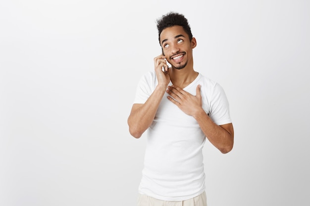 Тронутый и благодарный афро-американский парень разговаривает по телефону, реагирует на похвалы, благодарит