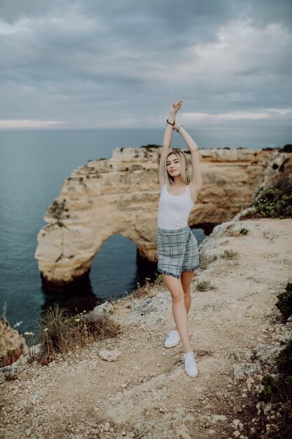 ポルトガル、ヨーロッパの観光。砂岩の岩の上のライフスタイル金髪女性観光客
