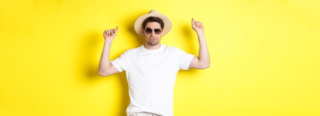 Free photo tourism travelling and holidays concept man tourist enjoying vacation dancing in straw hat and sungl