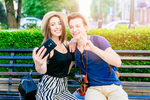 Free photo tourist couple on bench taking a selfie