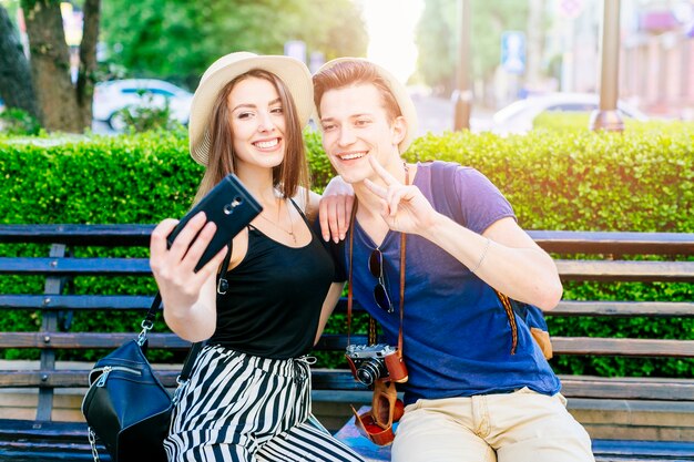 Tourist couple on bench taking a selfie