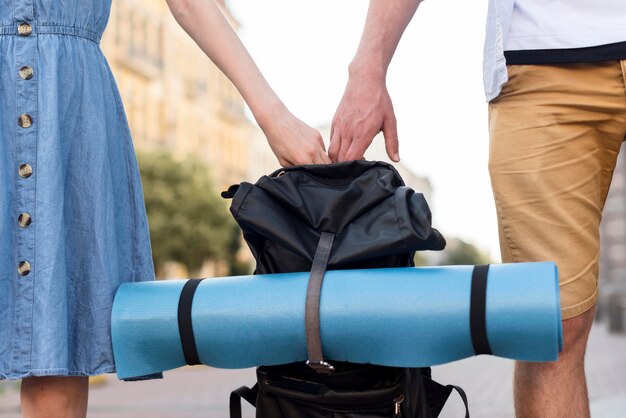 Tourist couple holding backpack together