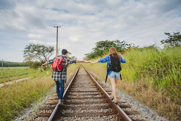 Tourist couple holding hands on train tracks