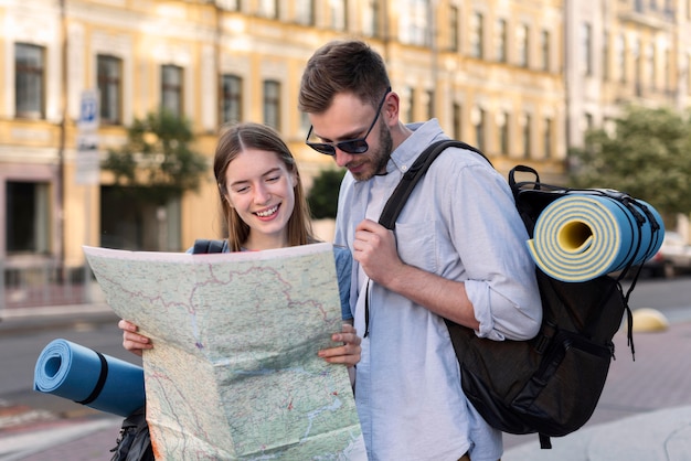 Tourist couple holding map while carrying backpacks