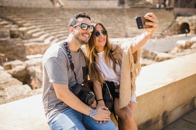 Tourist couple sitting together taking selfie through cell phone