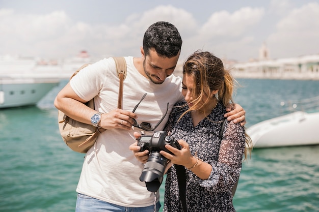 Coppie turistiche che stanno vicino al mare che guarda l'obbiettivo