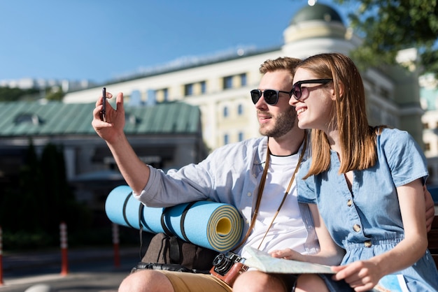 Foto gratuita coppie turistiche che prendono selfie all'aperto