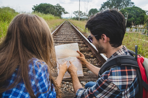 Бесплатное фото Туристическая пара с картой на железнодорожных путях
