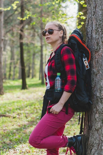 Tourist girl leaning against a tree