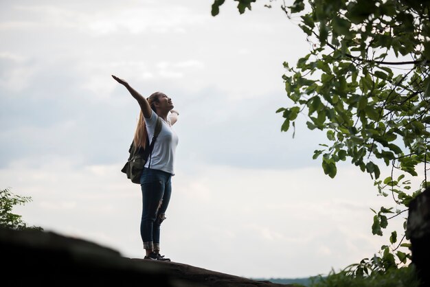 Tourist girl with arms happy with nature near the river. Travel concept.