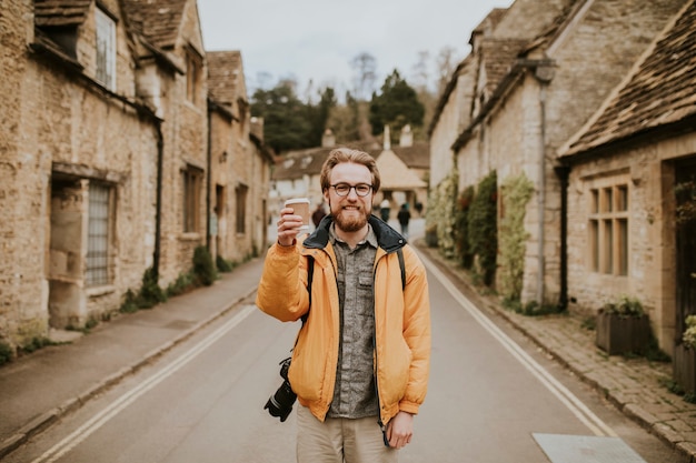 Free photo tourist holding coffee cup smiling in the village