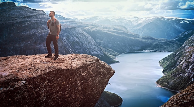 トロルトゥンガに立ってノルウェーのフィヨルドの美しい景色を楽しむ観光客の男性。