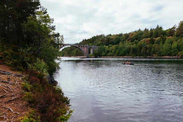 Tourist rowing the boat on the lake with green landscape