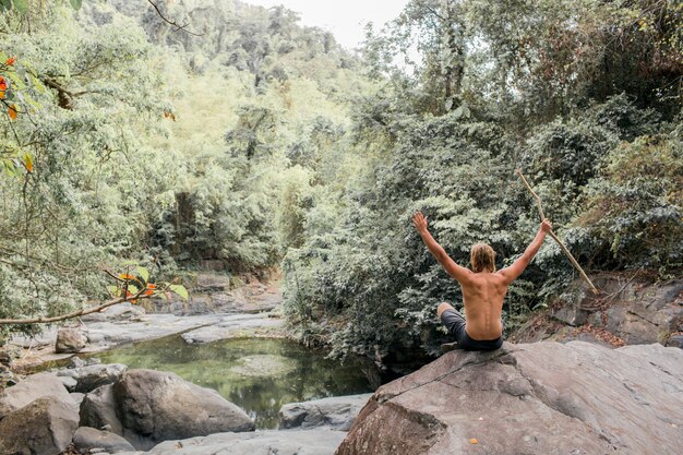 турист сидит на камне в лесу. Sumbawa