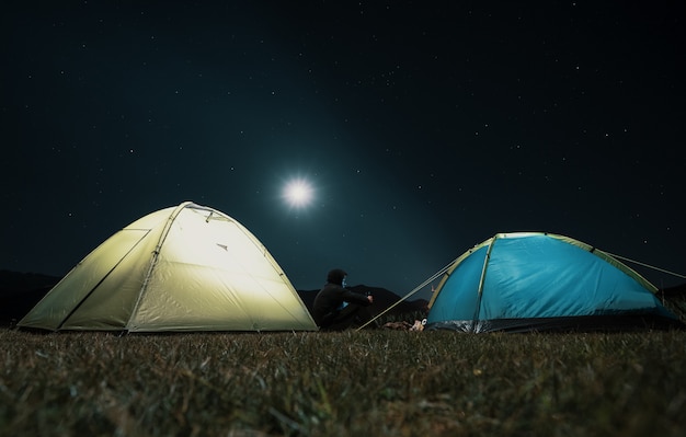 Tourist tents in camp among meadow in the night mountains