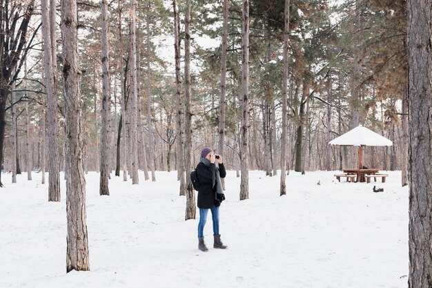 Tourist woman with binocular standing in the winter forest