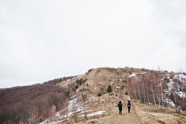 カルパティア山脈の雪に覆われた山の谷でハイキングをする観光客グループマコビツァの頂上からのウクライナのカルパティア山脈とヤレムチェの眺め