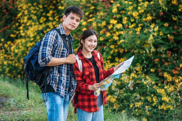 観光客の男性と女性は花畑の近くの地図を見ます。