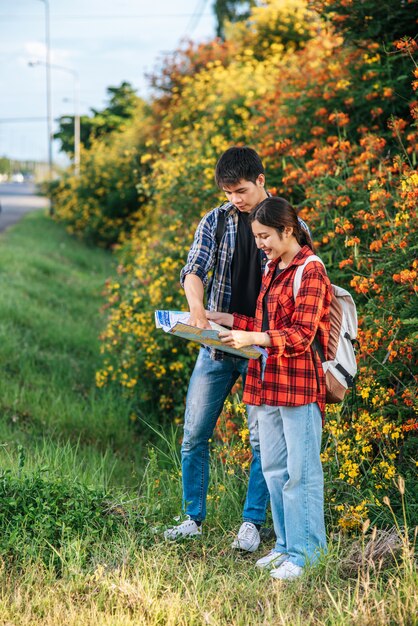 観光客の男性と女性は花畑の近くの地図を見ます。