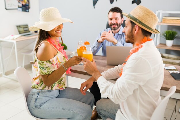 해변 휴가를 떠날 준비가 된 관광객들. 여행사에서 항공권을 구입한 후 하와이 옷을 입은 젊은 행복한 커플이 미모사로 건배를 하고 있다