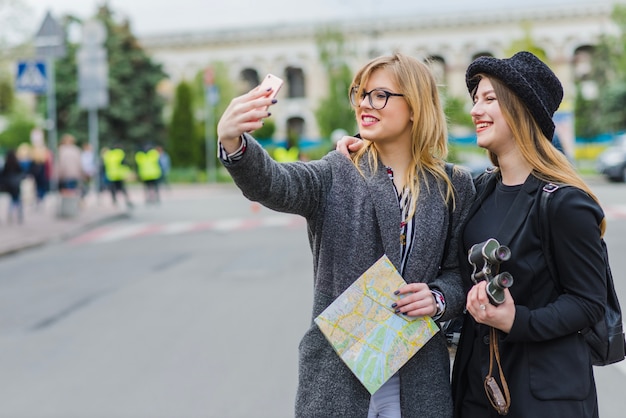 Tourists women taking selfie with map