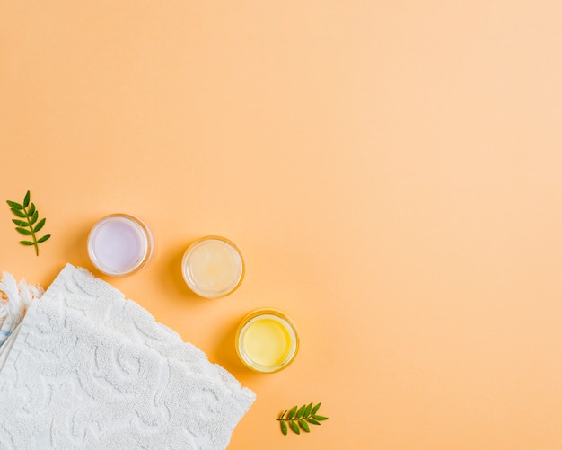 Towel and different moisturizers on colored background