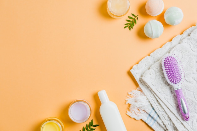 Towel; moisturizers; hairbrush and bath bomb on colored background