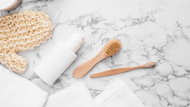 Towels; scrub glove; brush and cosmetic bottle on marble background