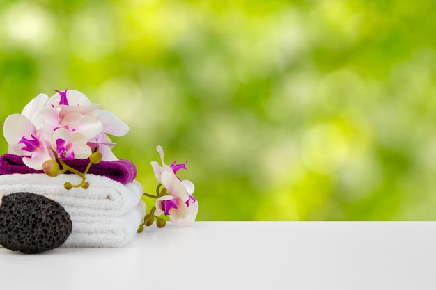 Towels with flowers on light table against blurred background