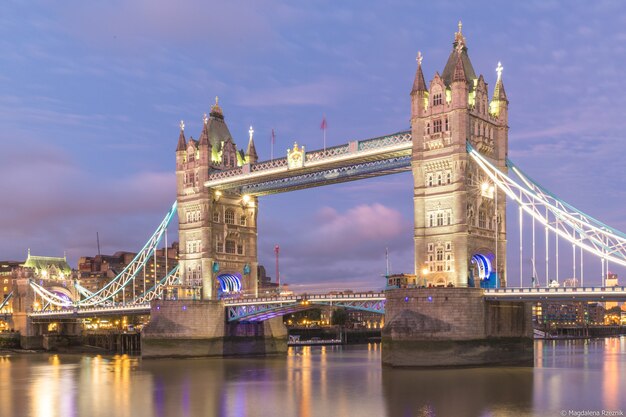 タワーブリッジはイギリスのロンドンで夜に建物とライトに囲まれています